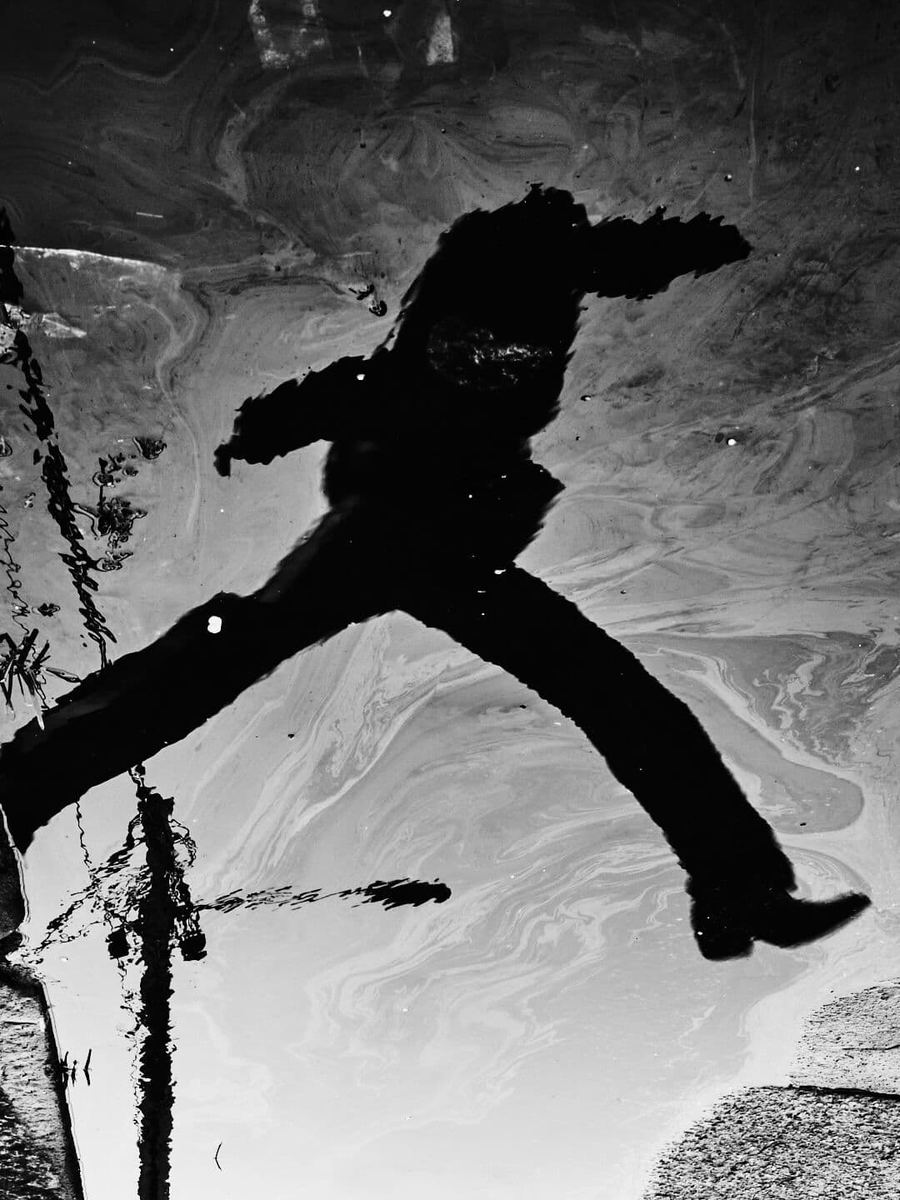 Puddle reflection of jumping silhouette